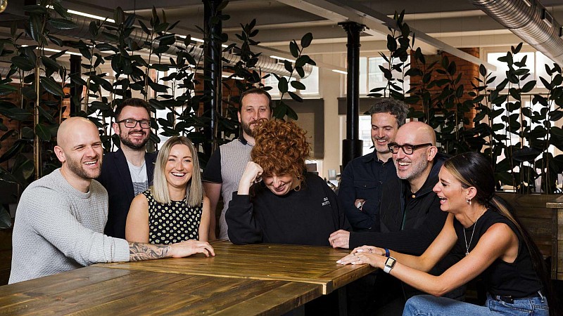 The Bring Digital team, sitting around a wooden table and laughing together