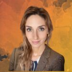 A woman with long, wavy hair, wearing a brown blazer, smiles gently at the camera against an abstract orange background.