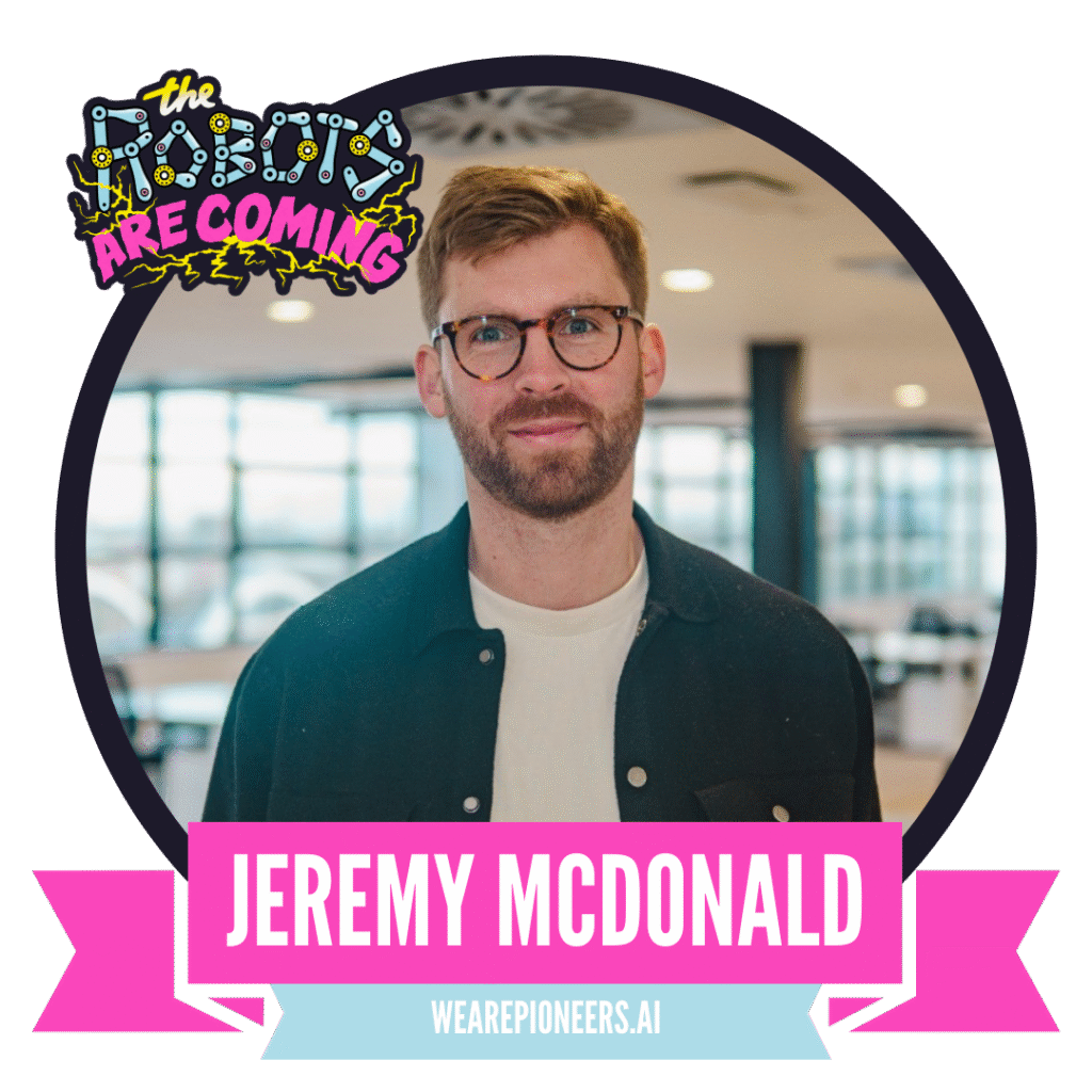 Man with glasses and beard, standing indoors, wearing a dark jacket over a white shirt. The image features colorful logos and text, including "The Robots Are Coming" and "Jeremy McDonald" with a website link, "wearepioneers.ai".