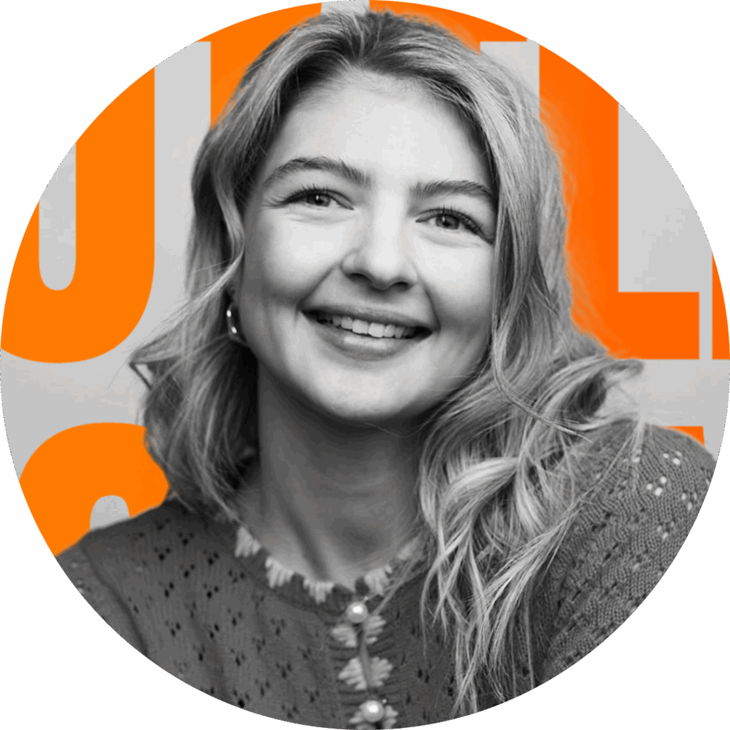 A smiling individual with wavy hair, wearing a textured sweater, is set against a bright orange background featuring bold text. The image is circular, focusing on the person's cheerful expression and engaging demeanor.