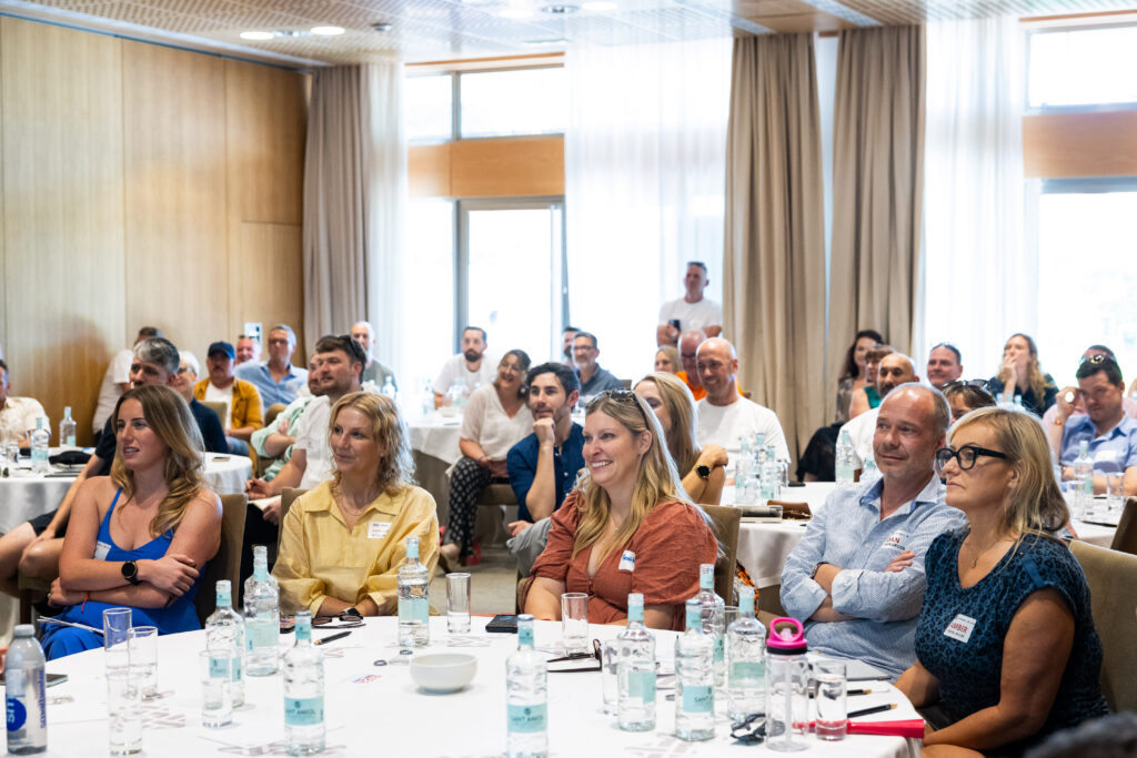 A group of people seated in a conference room, attentively listening to a presentation.